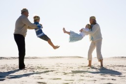 Besteforeldre leker med sine barnebarn på stranda
